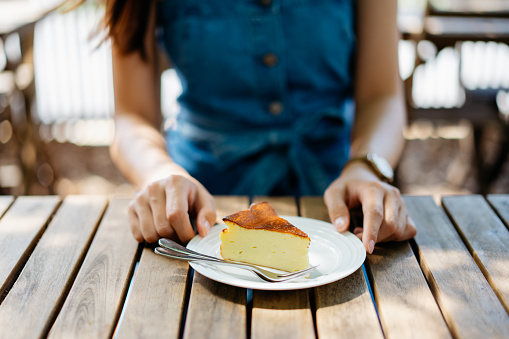 Young asian woman having a slice of cheesecake in cafe