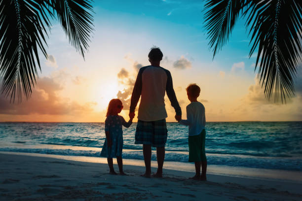 istock father and kids walking on beach at sunset 1255530280