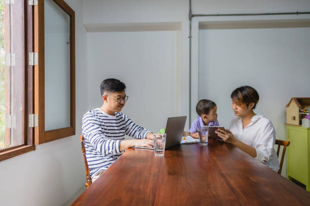 istock Happy moments young Asian family working with digital tablet and laptop computer while sitting in living room, Family relaxing and spending time together at home, Working from home concept 1255533104