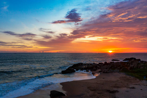 istock Colorful sunrise/sunset ocean beach with rocks, deep blue/orange sky. 1255533121