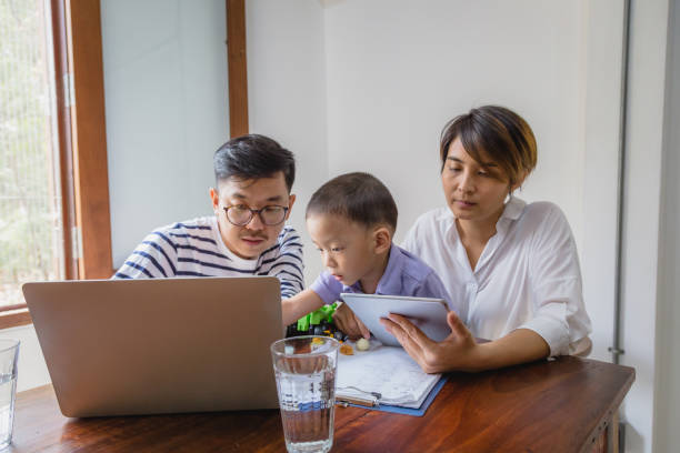istock Happy moments young Asian family working with digital tablet and laptop computer while sitting in living room, Family relaxing and spending time together at home, Working from home concept 1255534217