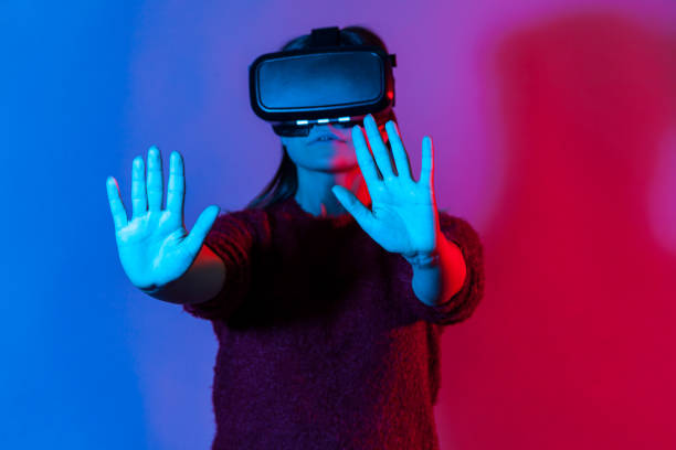 istock Girl with virtual reality glasses on head playing game simulator, standing outstretched hands, touching with palms 1255536245