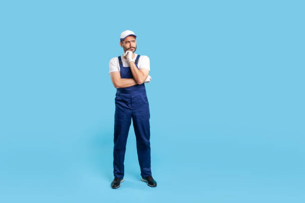 istock Full body pensive workman in overalls, cap and protective gloves standing, thinking intensely, pondering decision 1255536560