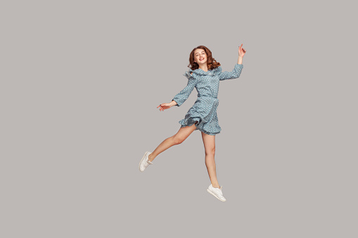 Feliz chica delicada en vestido de volante vintage levitando con movimiento de baile de ballet, flotando en el aire y sonriendo alegremente photo