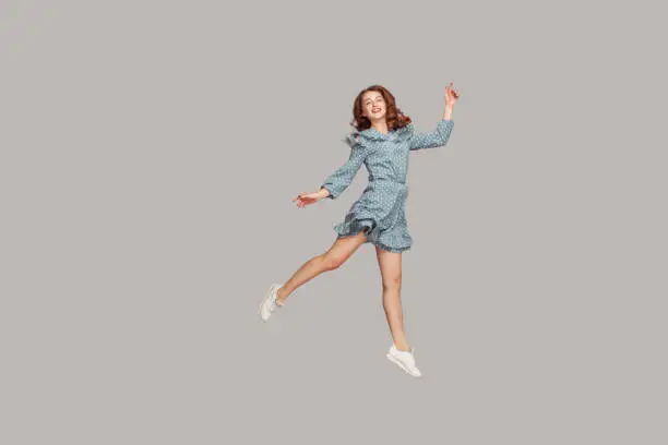 Photo of Happy delicate girl in vintage ruffle dress levitating with ballet dance move, hovering in mid-air and smiling joyfully