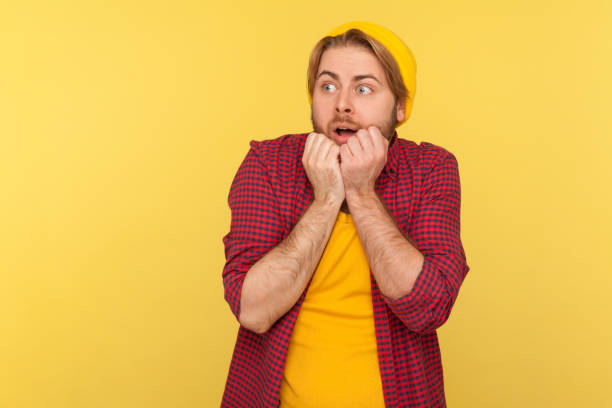 istock I'm afraid! Scared hipster coward guy in beanie hat and checkered shirt looking terrified panicking frightened 1255537834