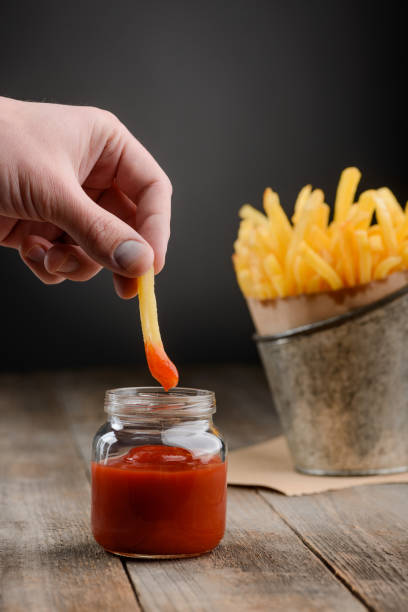 istock Hand dips appetizing French fries into ketchup 1255537927