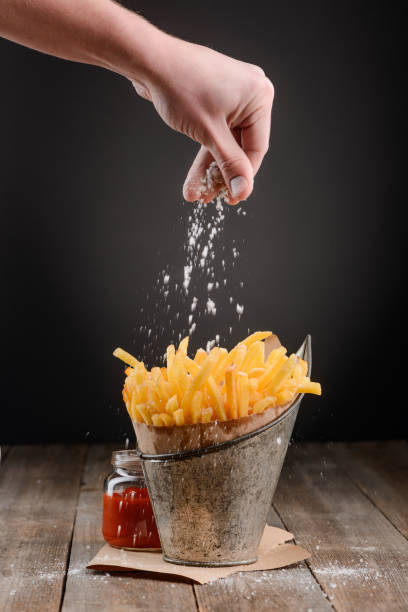 istock Hand sprinkles salt on fries 1255538044