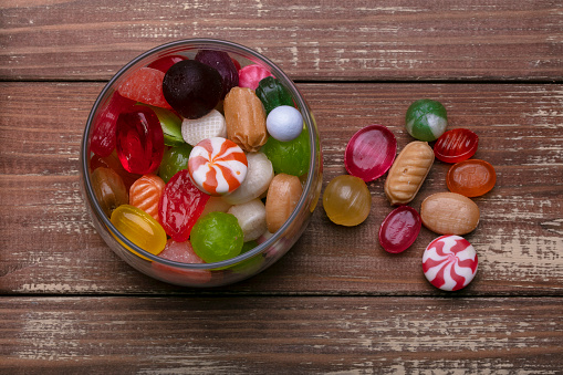 Candies in a jar on a wooden background. Multi-colored caramel. Sweets.