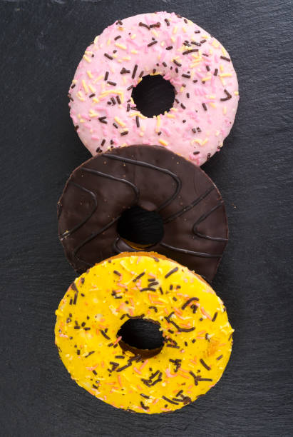 istock Homemade donuts with colored icing on black background. 1255541650