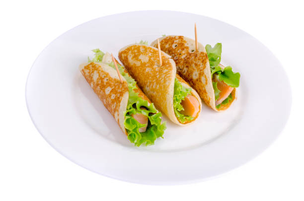 istock Snack rolls from pancakes, salmon and green salad leaves. 1255542097