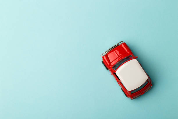 Red small toy car on blue background, postcard concept, copy space