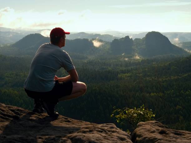 istock Hiker Man Take A Rest On Mountain Peak. Man Sit On Summit, Bellow Spring Valley. Sun Shining In Sky. 1255546701