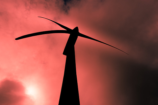 Wind turbine under a threatening red sky underlining conservation theme.