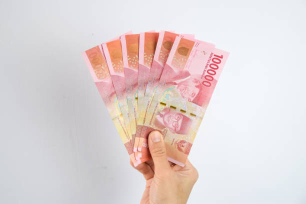 donna che tiene e mostra 100.000 rupie indonesiane - indonesian currency foto e immagini stock