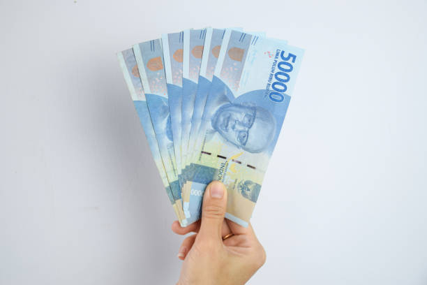 Orang memegang uang Rp50.000 sejumlah Rp300.000 sebagai bentuk memulai strategi investasi.