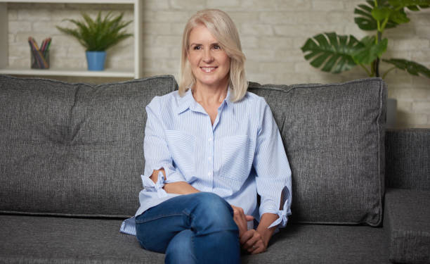 istock Pretty middle aged woman is sitting on a sofa at home 1255555801