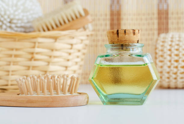 Vintage glass bottle with cosmetic oil (massage oil, tincture, infusion, extract) and wooden hair brush. Aromatherapy, homemade spa and herbal medicine concept. Copy space. Vintage glass bottle with cosmetic oil (massage oil, tincture, infusion, extract) and wooden hair brush. Aromatherapy, homemade spa and herbal medicine concept. Copy space. castor oil stock pictures, royalty-free photos & images