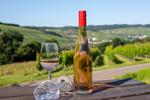 Wine bottle with glasses on wooden table with landscape on river moselle in background