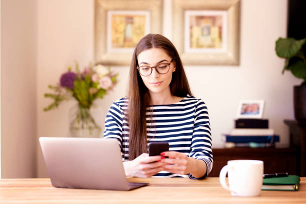 istock Businesswoman sitting at desk and text messaging while working from home 1255561722