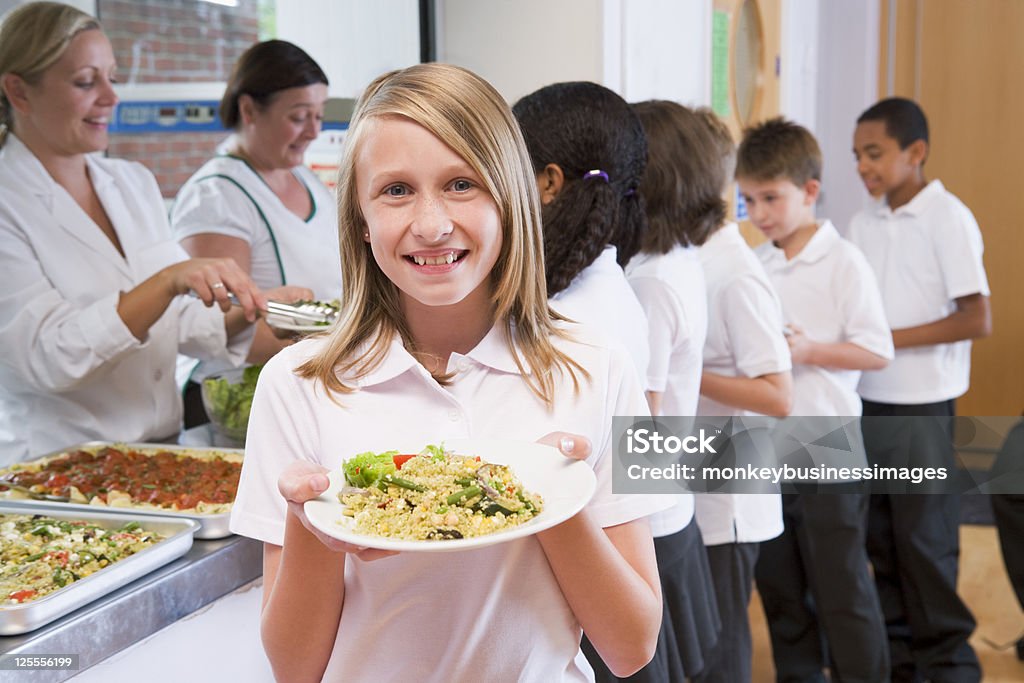 Écolière tenant la plaque de déjeuner à la cafétéria de l'école - Photo de Cantine scolaire libre de droits