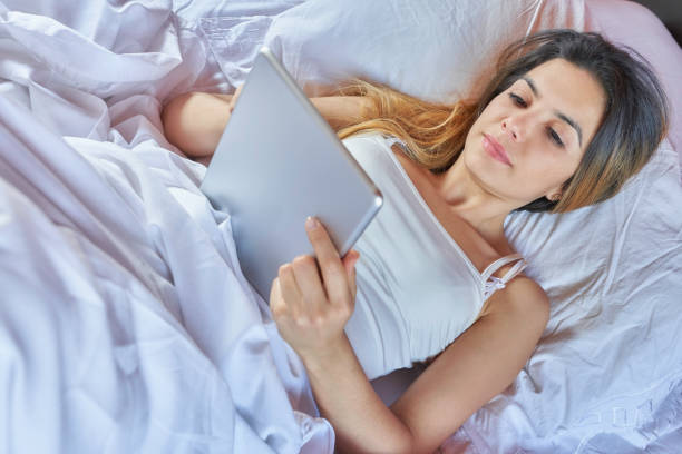 istock Hispanic cute young woman text messaging on digital tablet while lying on her bed 1255563716
