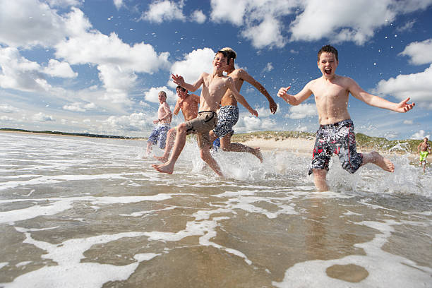 Teenage boys playing on beach stock photo