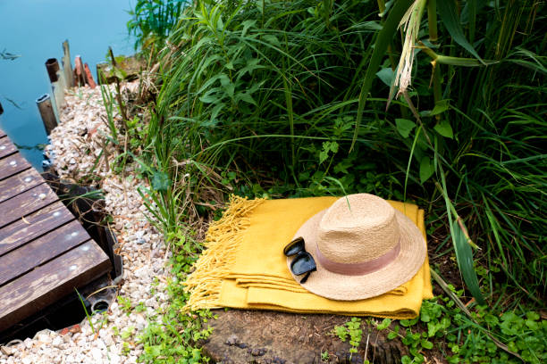 High angle shot of straw hat and sunglasses on the lakesshore. Summer vacation concept.