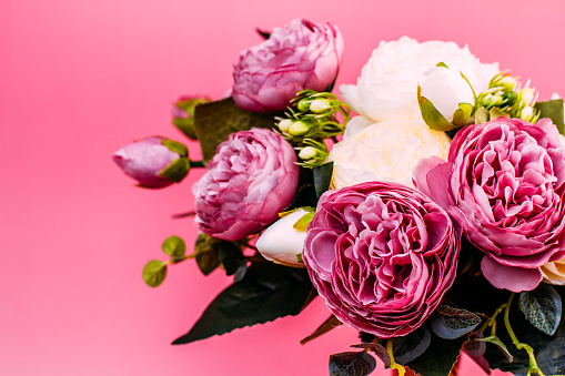 artificial  pink and white peonies on a pink background