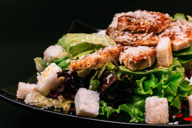 caesar salad on a black tartlet and black background - chicken salad grilled chicken grilled imagens e fotografias de stock