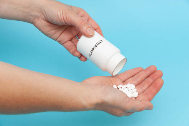 istock Treatments for Coronavirus (COVID-19): Azithromycin - White plastic packaging bottle in the hands with tablets. 1255568926