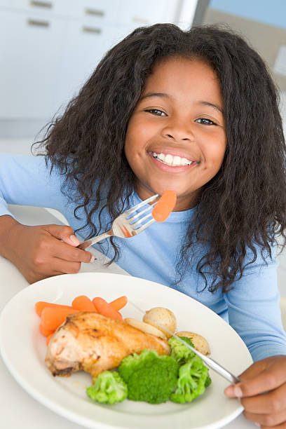 istock Girl in kitchen eating chicken and vegetables 125557089