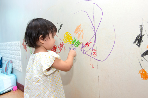 little baby boy and girl drawing with crayon color on the wall
