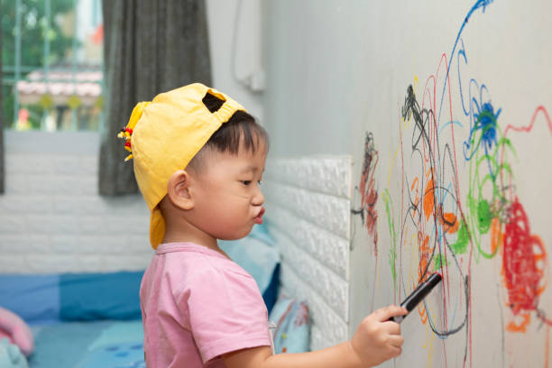 little baby  boy drawing with crayon color on the wall
