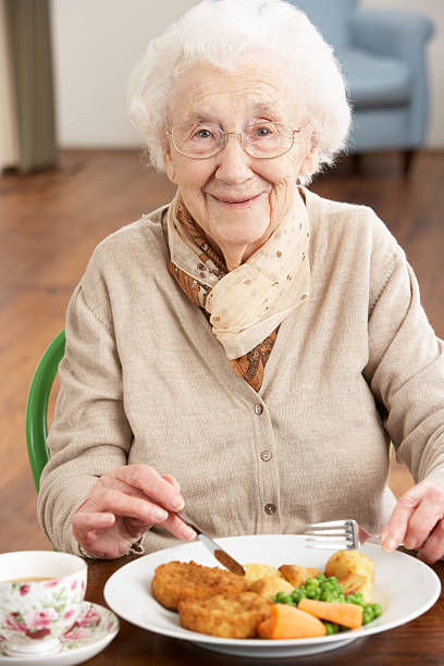 Senior Woman Enjoying Meal Smiling To Camera