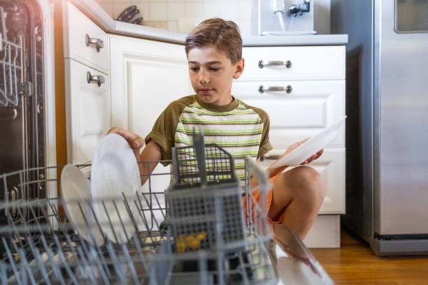 istock Little boy loading the dishwasher at home 1255572212