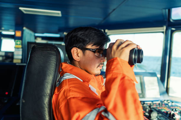 istock Filipino deck Officer on bridge of vessel or ship looking through binoculars 1255572975