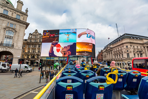 London, UK - Feb 22, 2018: Tourists enjoying the ride on an open-air double decker Tour Bus in London.