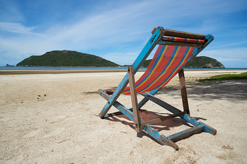 A wooden beach chair on the beach in sunny day and blue sky background
