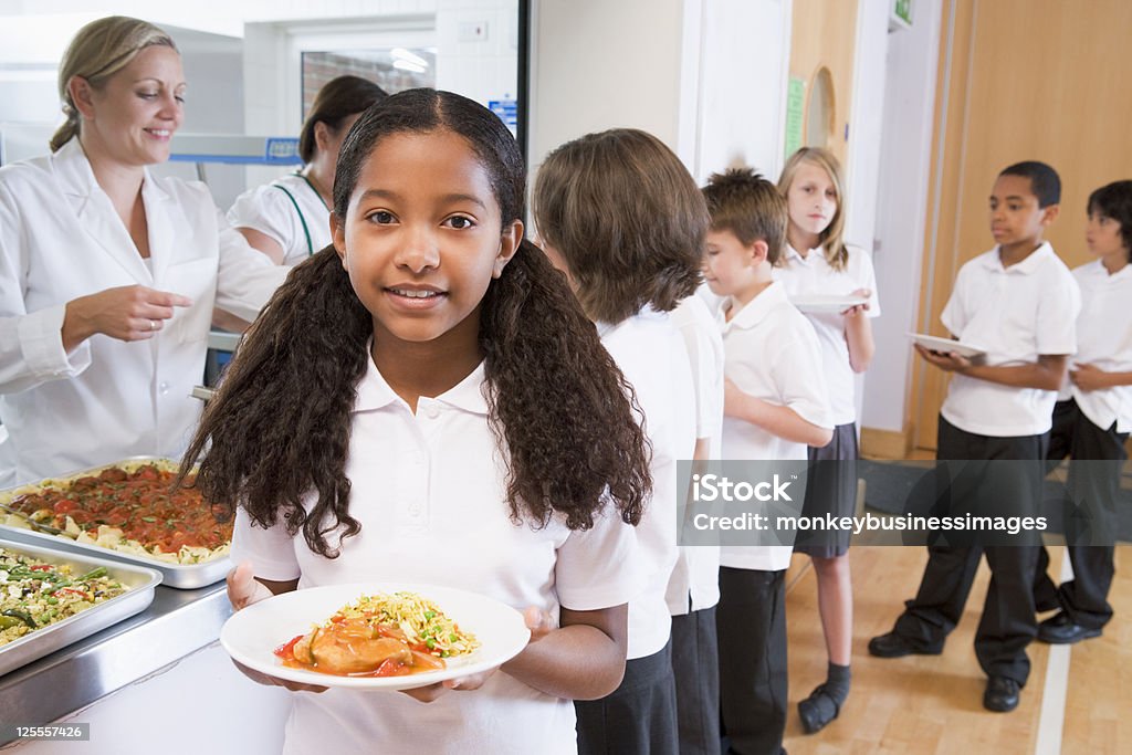 Aluna segurando o prato do almoço no refeitório da escola - Foto de stock de Merenda Escolar royalty-free