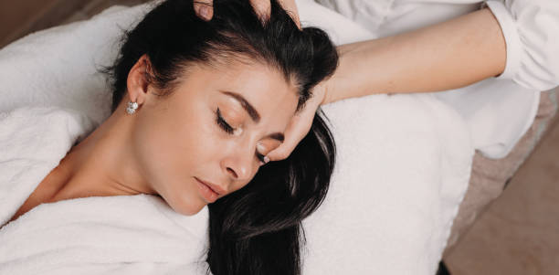 istock Head massage session with a charming brunette lady lying on the spa couch with closed eyes 1255576989