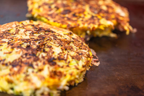 omelete japonesa okonomiyaki cozida em ambos os lados em um prato quente. - pizza tuna prepared fish cheese - fotografias e filmes do acervo