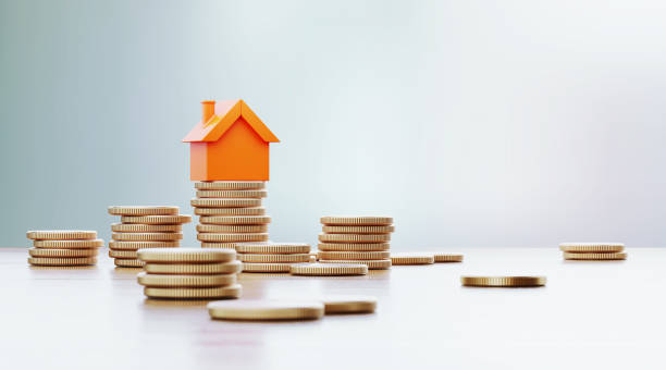 casa giocattolo color arancione seduta sopra pile di monete: assicurazione e concetto immobiliare - prezzo messaggio foto e immagini stock