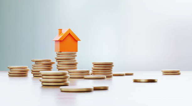 Orange Colored Toy House Sitting over Coin Stacks: Insurance And Real Estate Concept Orange toy house is sitting over coin stacks. Horizontal composition with selective focus and copy space. Real Estate and Insurance concept. mortgage stock pictures, royalty-free photos & images