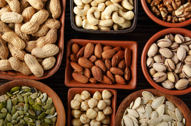 istock Flat lay view at assorted nuts and seeds in clay bowls on wooden kitchen table 1255580490