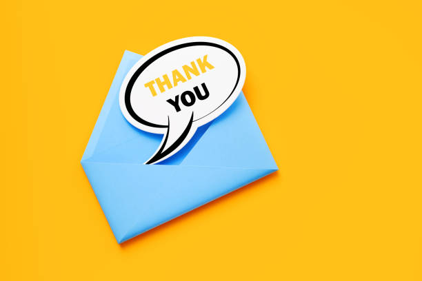 istock Blue Envelope and Speech Bubble Shaped Thank you Note Sitting on Yellow Background 1255581321