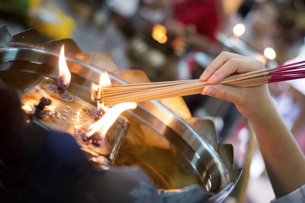 女の子のグリップと寺院のオイルランプに燃える火から香スティックを点灯 - burning temple incense buddhism ストックフォトと画像