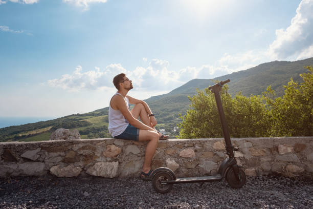 istock Young man riding an electric scooter on mountain range. Ecological transportation concept 1255586318