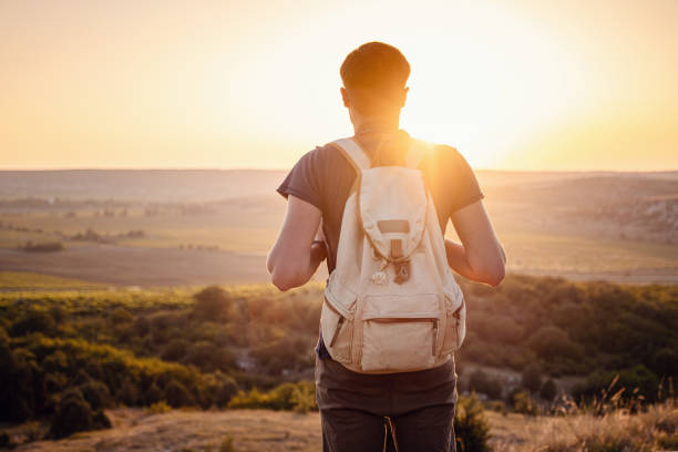 istock A man standing on a mountain as the sun sets. 1255586490
