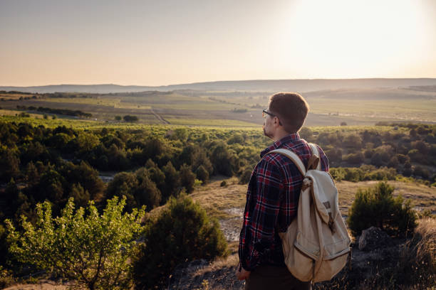 istock A man standing on a mountain as the sun sets. 1255587131